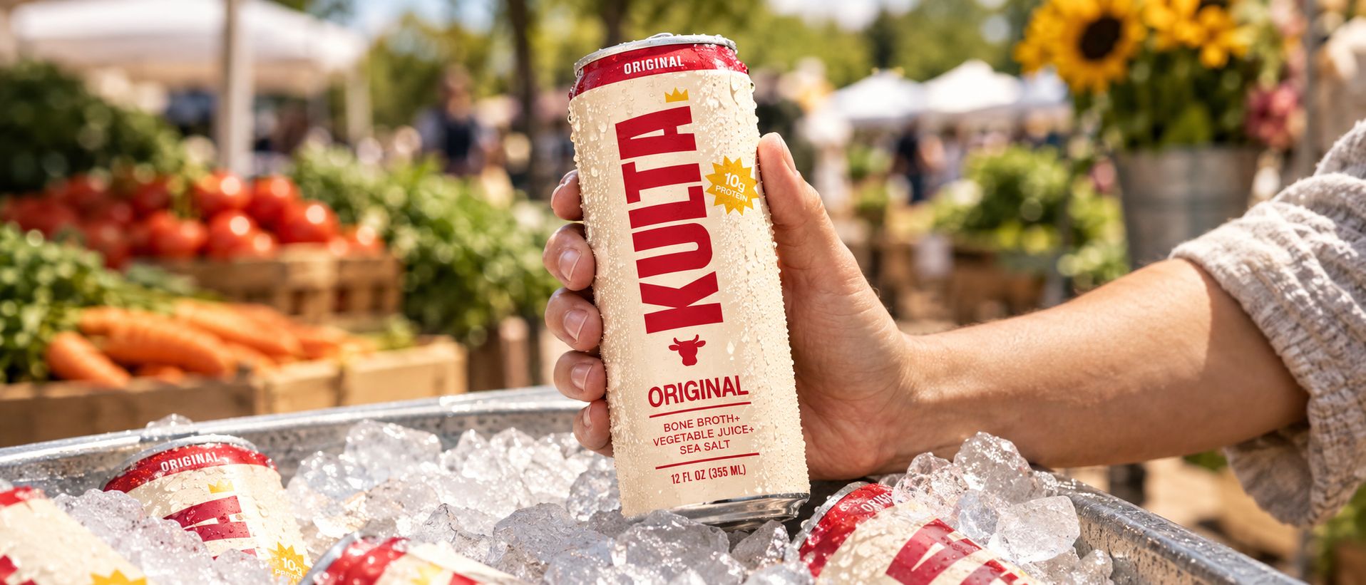 A hand pulling a cold can of Kulta from a cooler of ice at a market