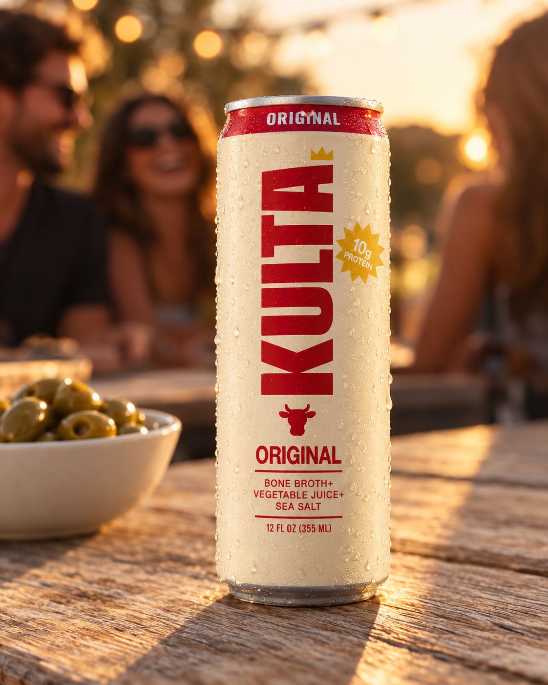 A cold can of Kulta on a patio table at golden hour, friends laughing behind