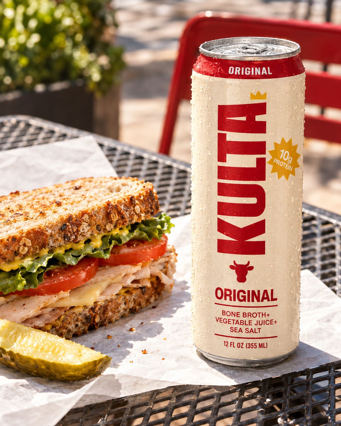 A can of Kulta next to a sandwich at an outdoor lunch table